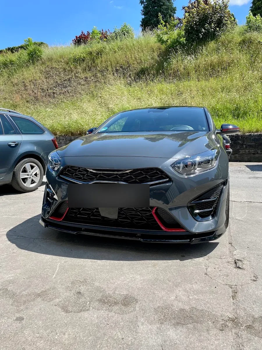 Grauer Kia ProCeed GT frontal auf dem Hof bei Sonne, Lack sauber und glaenzend.