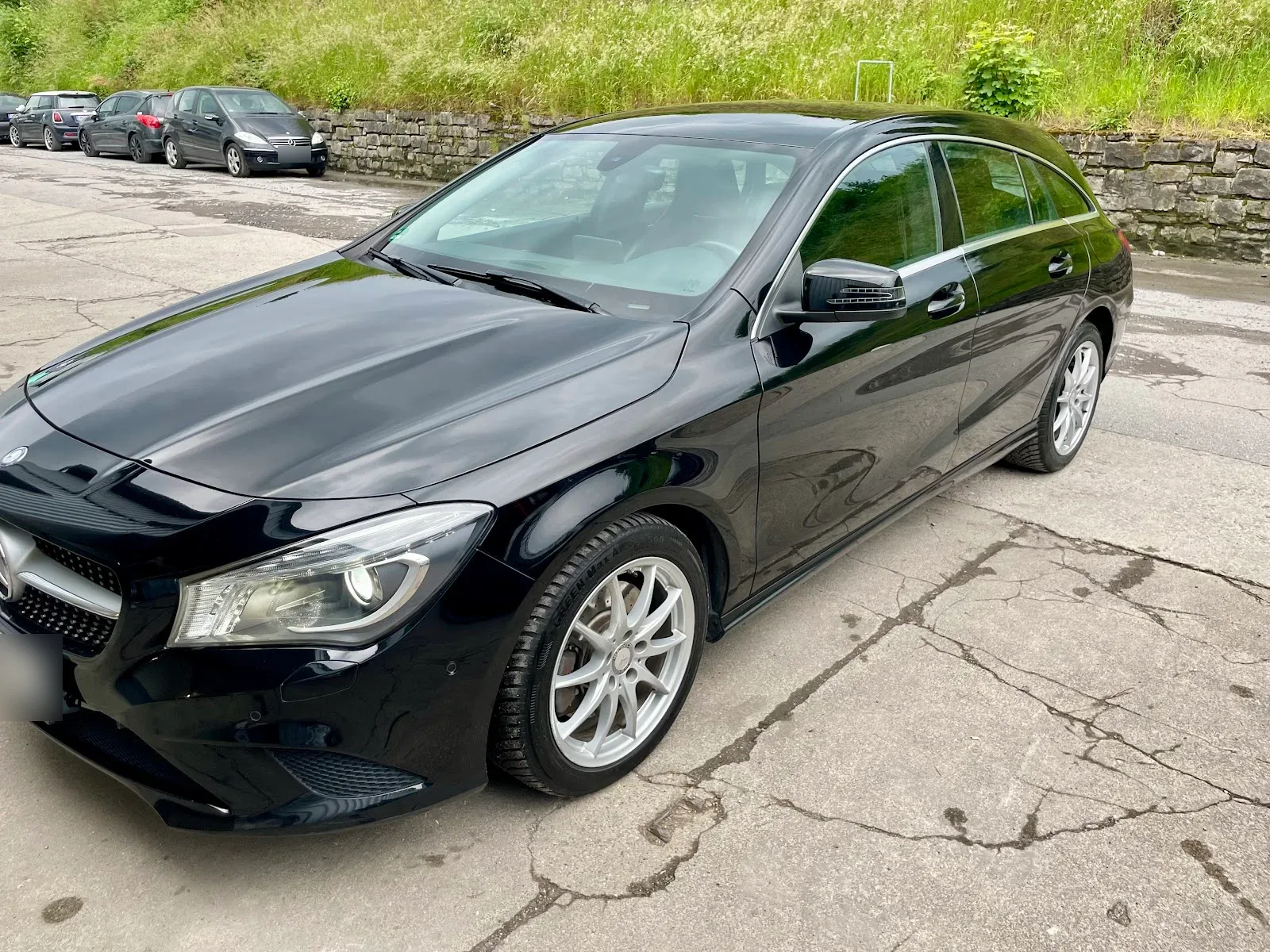 Schwarzer Mercedes CLA Shooting Brake in Dreiviertelansicht auf dem Hof, Lack tief glänzend, silberne Felgen.