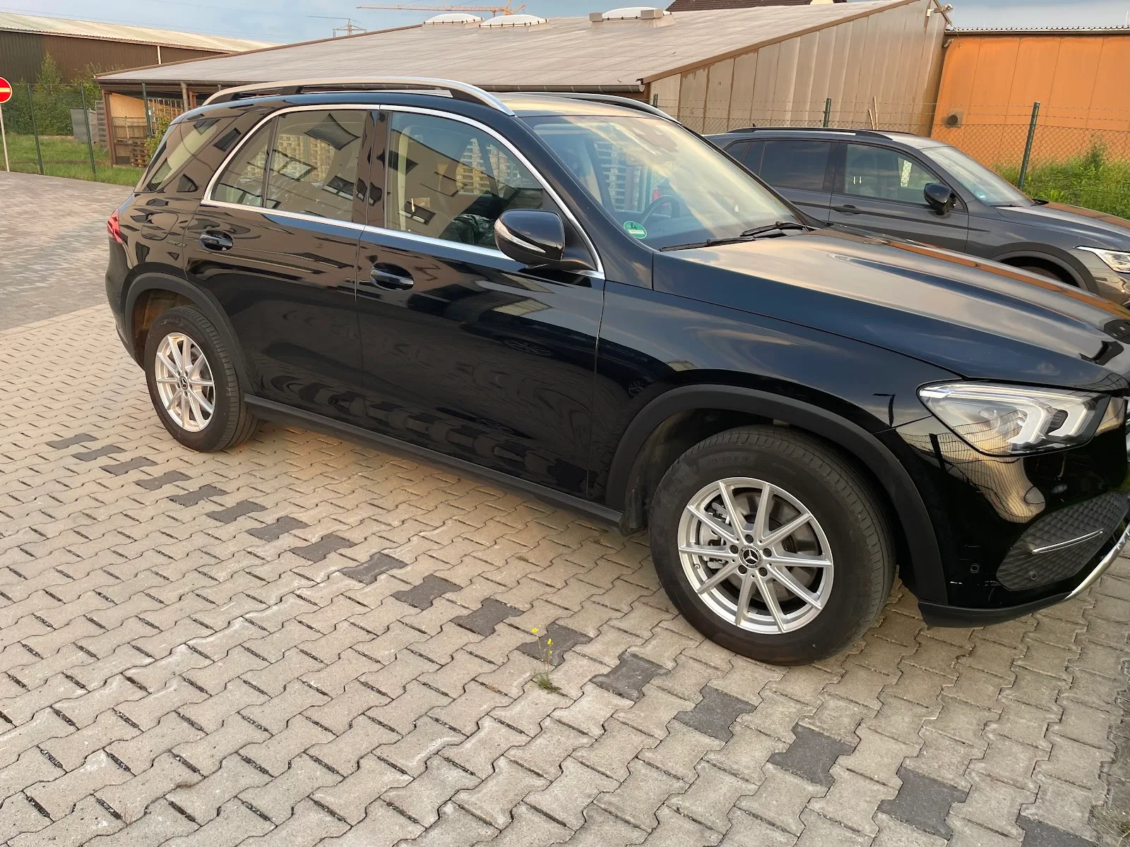 Schwarzer Mercedes GLE SUV in Seitenansicht mit tief spiegelndem Lack auf Pflastersteinen.