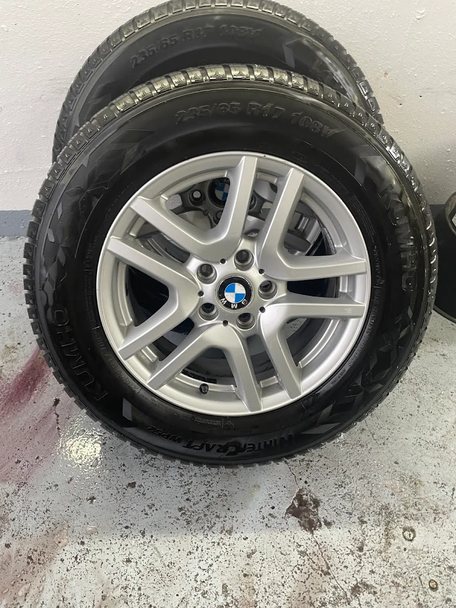 Zwei gereinigte BMW-Alufelgen mit Kumho-Winterreifen stehen an einer Hallenwand zur Einlagerung.