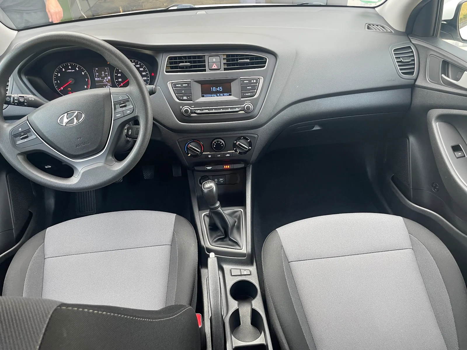 Frisch gereinigtes Cockpit eines Hyundai i20 mit staubfreiem Armaturenbrett, sauberen Stoffsitzen und leeren Fussraeumen.