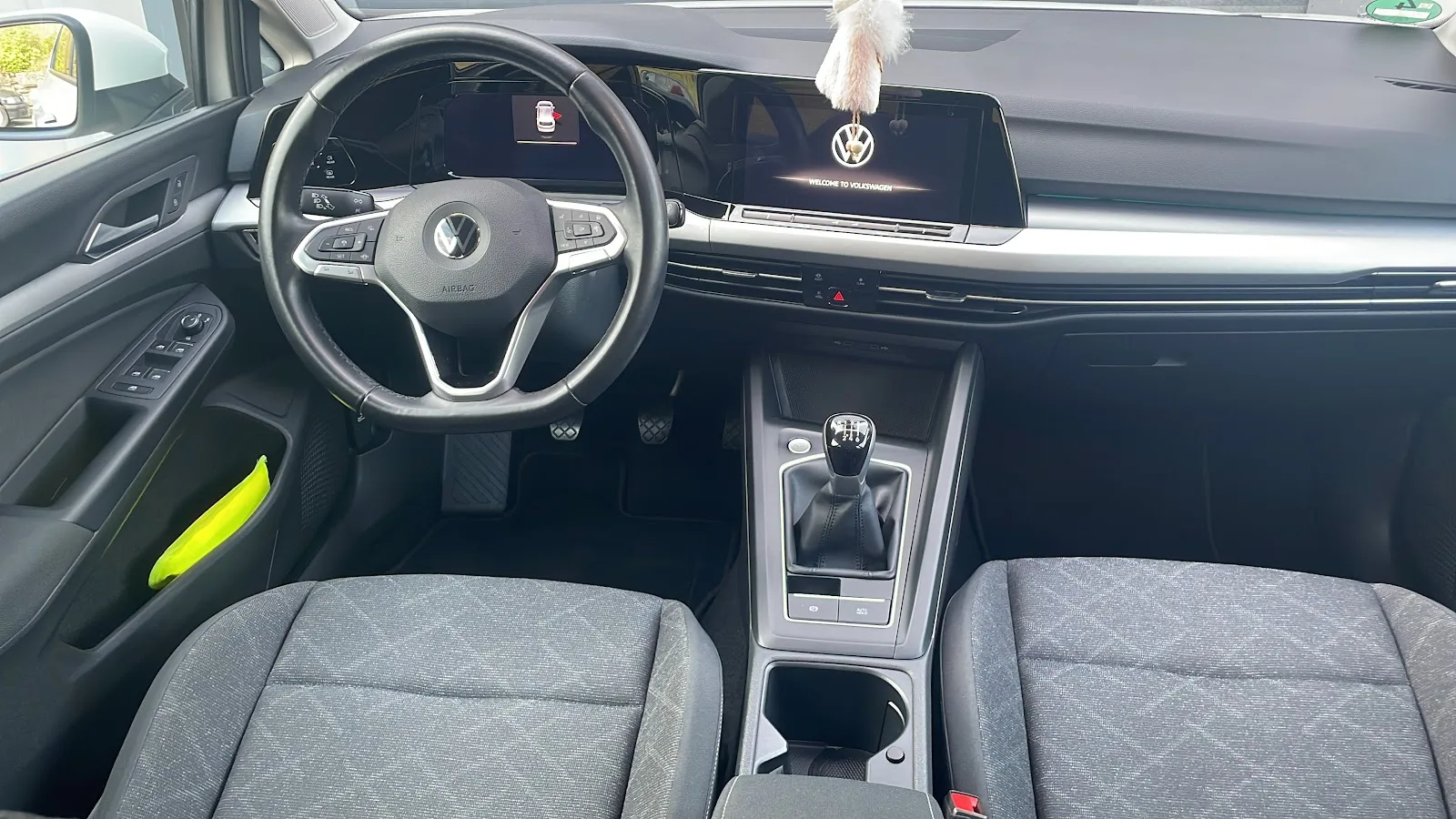 Aufgeraeumtes Cockpit eines VW Golf 8 mit gereinigtem Armaturenbrett, Lenkrad, Mittelkonsole und Stoffsitzen.