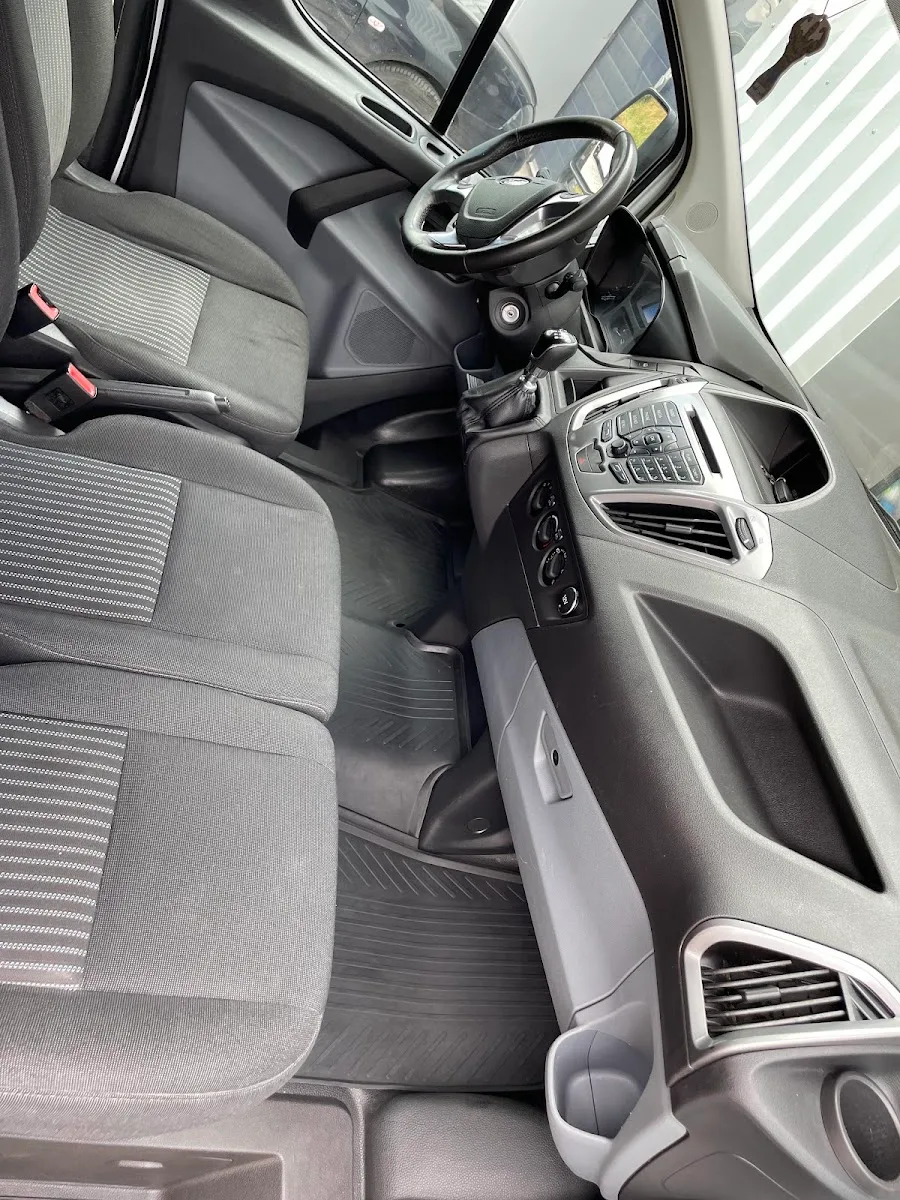 Gereinigtes Fahrerhaus eines Ford Transit mit Stoffsitzen, sauberem Armaturenbrett und Gummimatten.