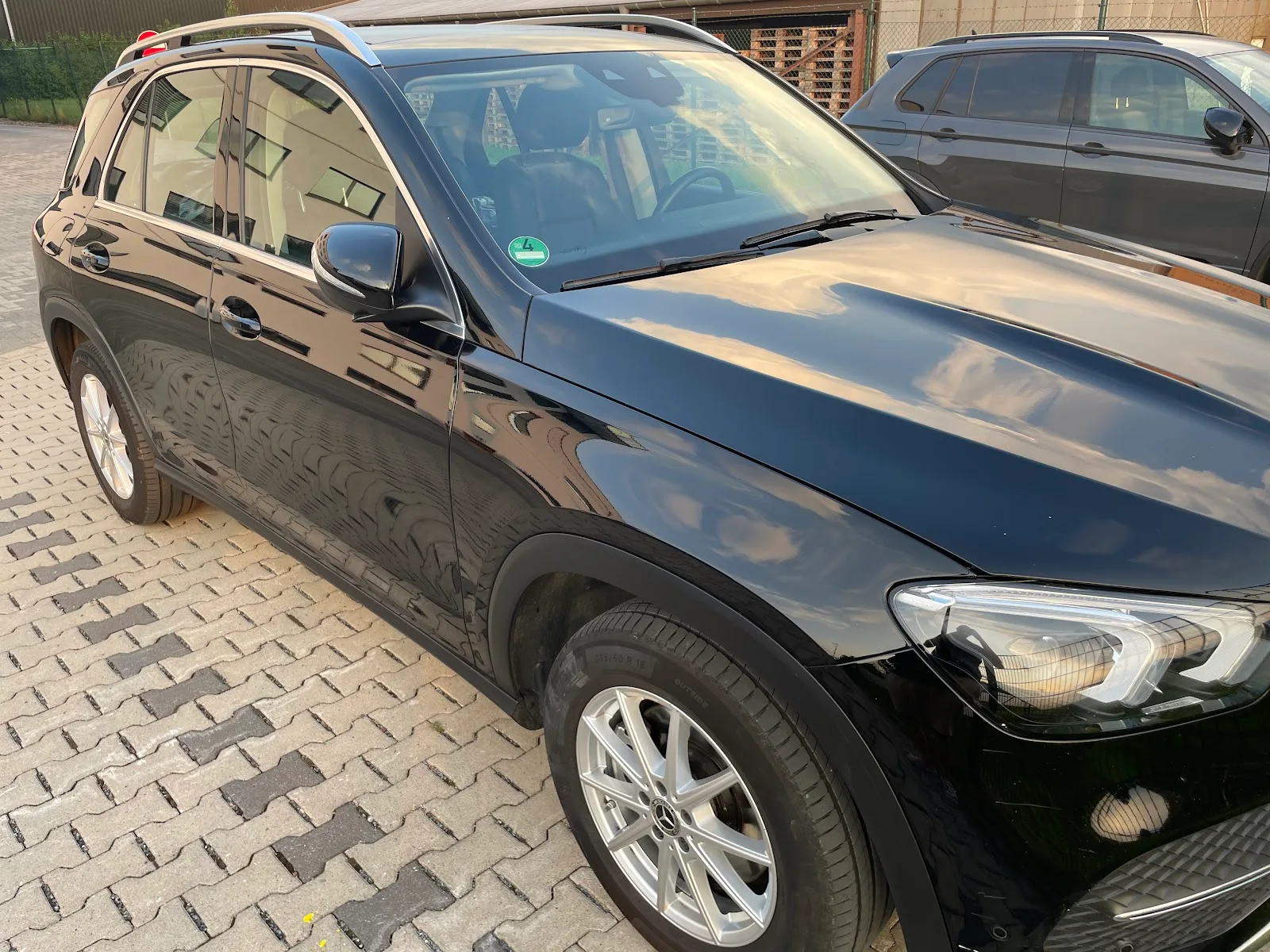 Schwarzer Mercedes GLE in Nahaufnahme der Seite und Motorhaube, Lack spiegelt Himmel und Wolken nach der Politur.