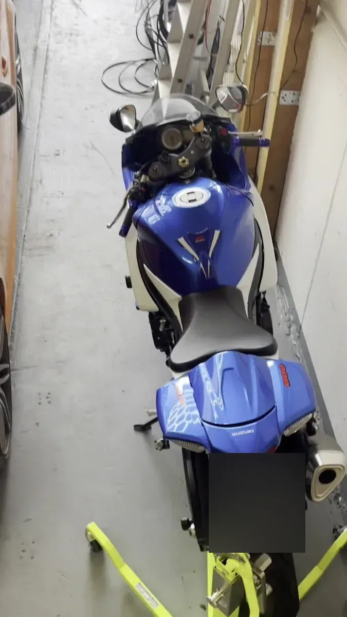 Blau-weisse Suzuki GSX-R Supersportmaschine auf einem Montagestaender in der Halle, von schraeg oben fotografiert.