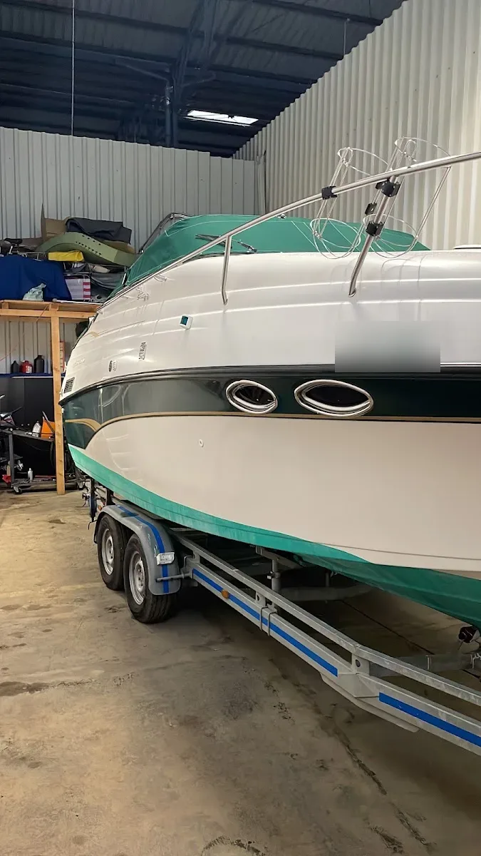 Weiss-gruenes Motorboot auf Trailer in einer Halle, Rumpf poliert und glaenzend.