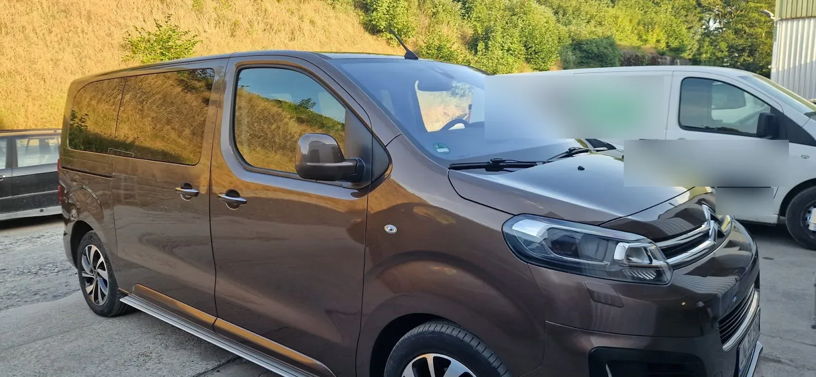 Brauner Citroen SpaceTourer Transporter mit hochglaenzendem Lack im Abendlicht, daneben ein Firmen-Transporter.