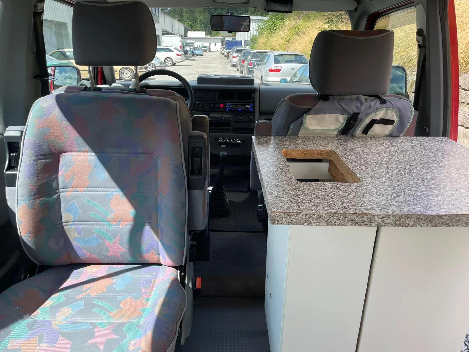 Innenraum eines VW T4 California Campers mit gereinigten gemusterten Stoffsitzen, Kuechenblock und Cockpit.